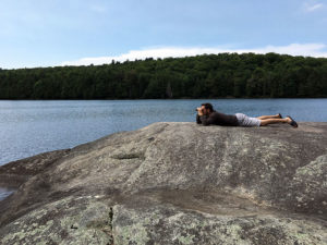 Lying on rock by the water looking through binoculars