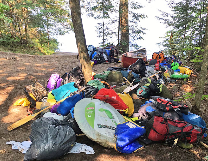 Large group travelling with tons of gear at the end of the portage into Cache Lake in Algonquin Park