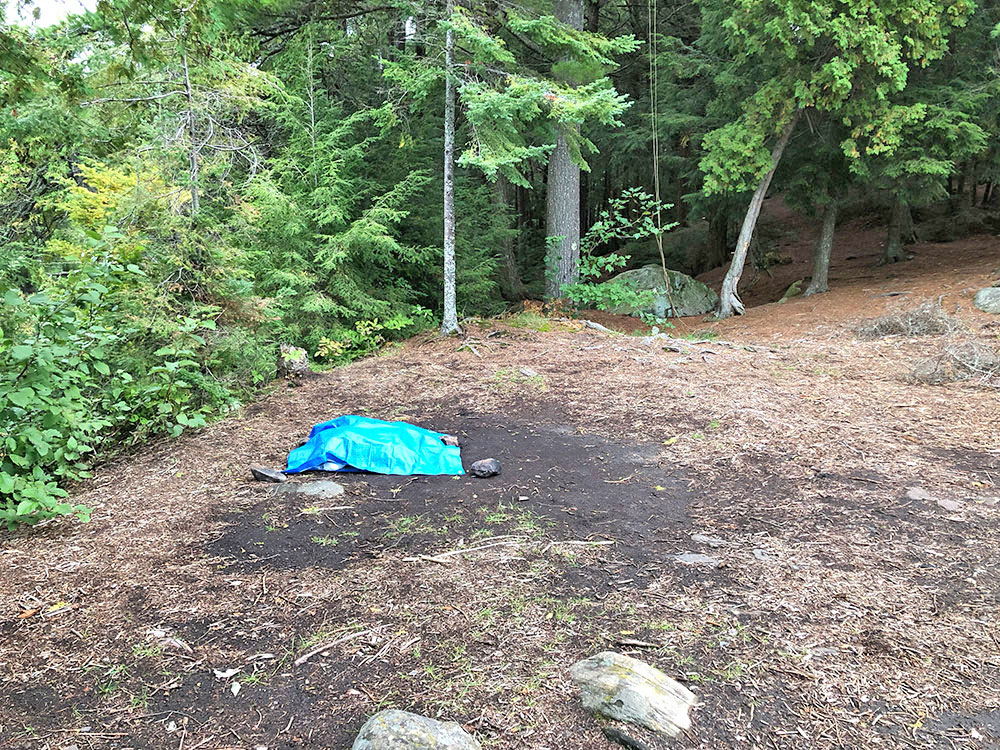 Flat tent spot with blue tarp on Otterslide Lake campsite