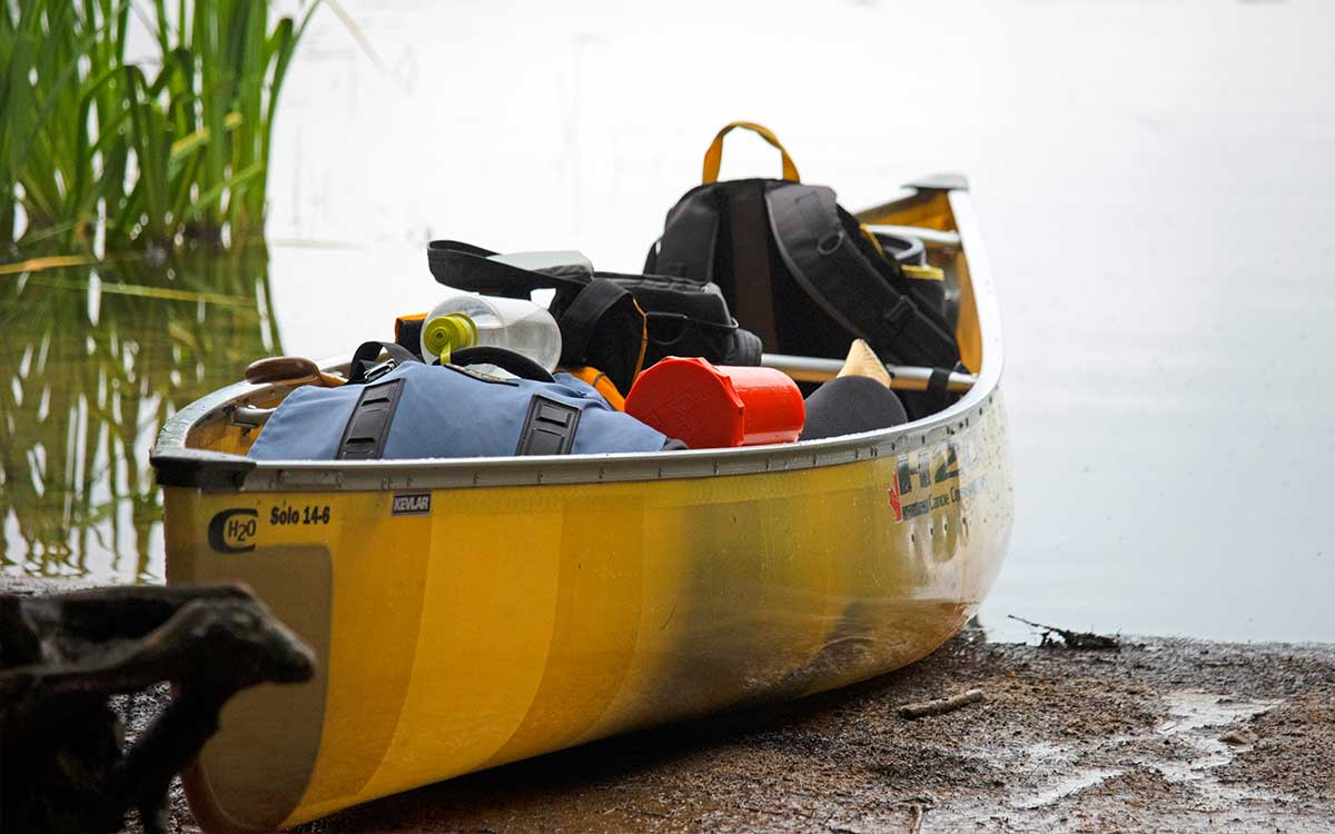 Renting Canoes in Algonquin Park - Yellow H2O Canoe loaded with gear on beach landing after finishing a portage