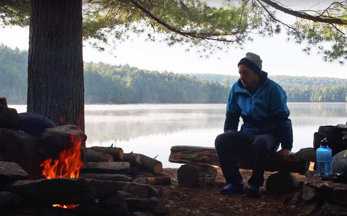 Solo Canoe Trip Tips - sitting by the fire on a solo canoe trip in Algonquin Park