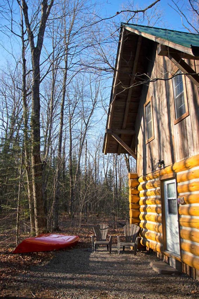 Loon East cabin at Wolf Den Nature Retreat with red canoe outside April 2022