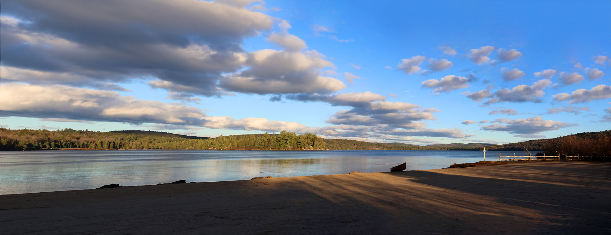Panorama of the sunny blue skies with a canoe at the Lake of Two Rivers Campground beach in Algonquin Park, October 2023