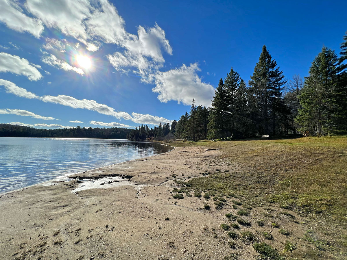 Sandy beach at Whitefish Lake Campground during a sunny day, in Algonquin Park October 2023